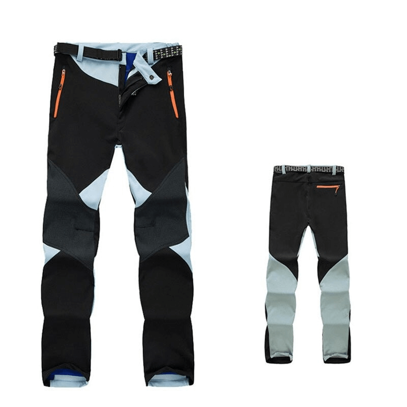 Women's black and grey softshell skiing pants with orange zipper accents, ideal for outdoor trekking and skiing adventures.